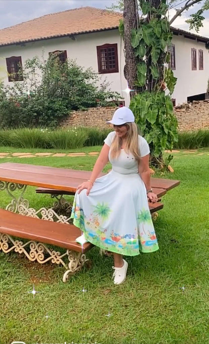 Vestido branco em jardim com casa ao fundo, com rostinho de nuvem no peito e animais na barra.