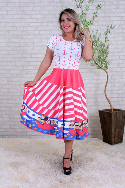 Modelo em sala de parede de tijolinho veste vestido com âncoras na blusa, saia listrada e barco com crianças na barra.
