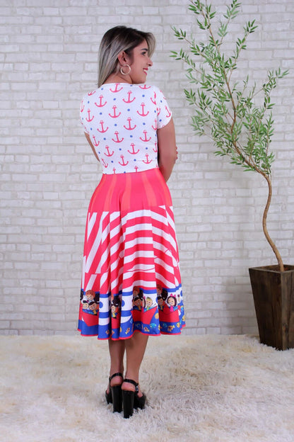 Costas do vestido com âncoras e bolinhas azuis na blusa, saia com listras e crianças num barco na barra azul-marinho.